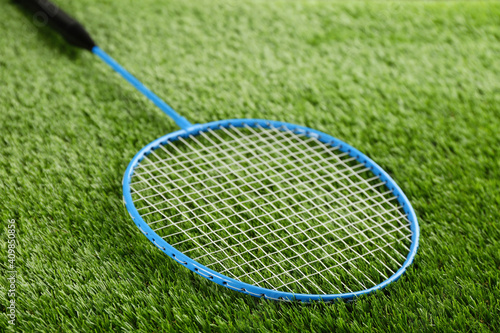 Badminton racket on green grass outdoors, closeup