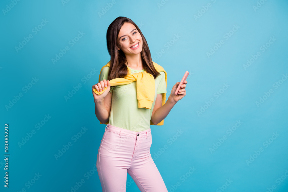Photo of young beautiful pretty happy positive smiling girl blogger hold smartphone isolated on blue color background Photo of young beautiful pretty happy positive smiling girl blogger hold smartphone isolated on blue color background