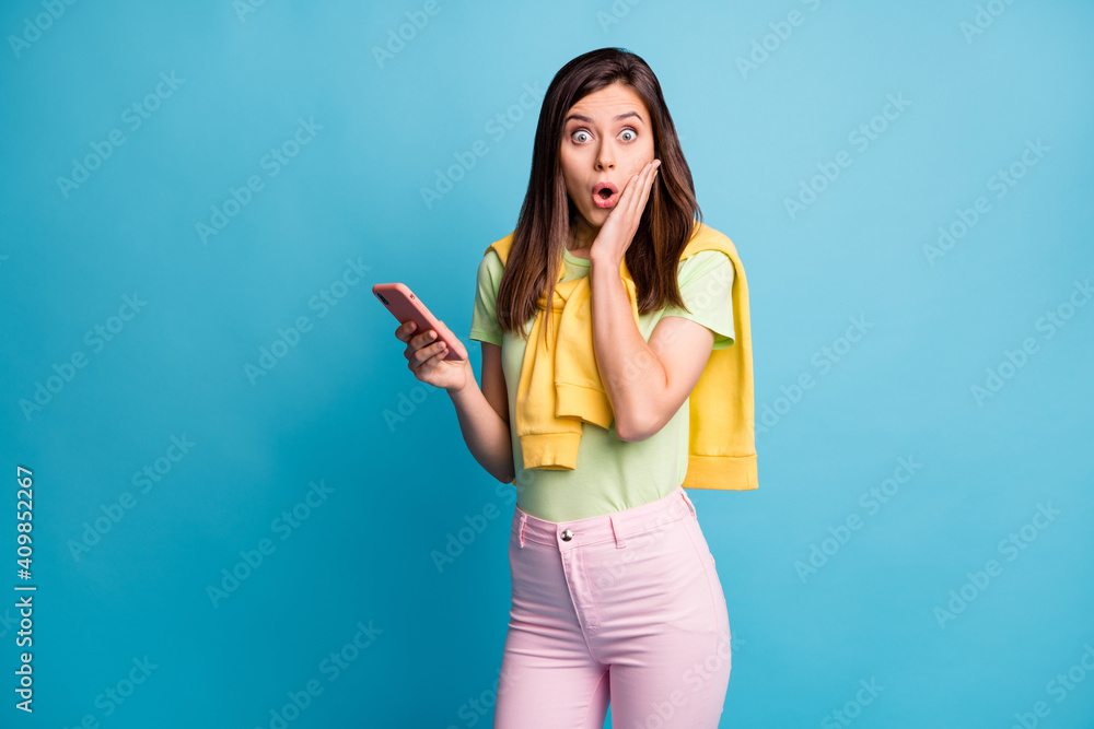 Portrait of attractive amazed girl using device browsing web news pout lips isolated over bright blue color background Portrait of attractive amazed girl using device browsing web news pout lips isolated over bright blue color background