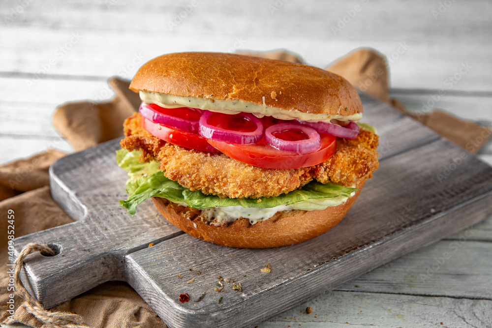 Tasty grilled burger with chicken, turkey, or breaded fish fillets. Delicious grilled hamburger on a dark background. Free space for text Tasty grilled burger with chicken, turkey, or breaded fish fillets. Delicious grilled hamburger on a dark background. Free space for text