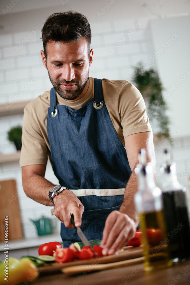 Portrait of handsome man in kitchen. Young man preparing salad. Portrait of handsome man in kitchen. Young man preparing salad.