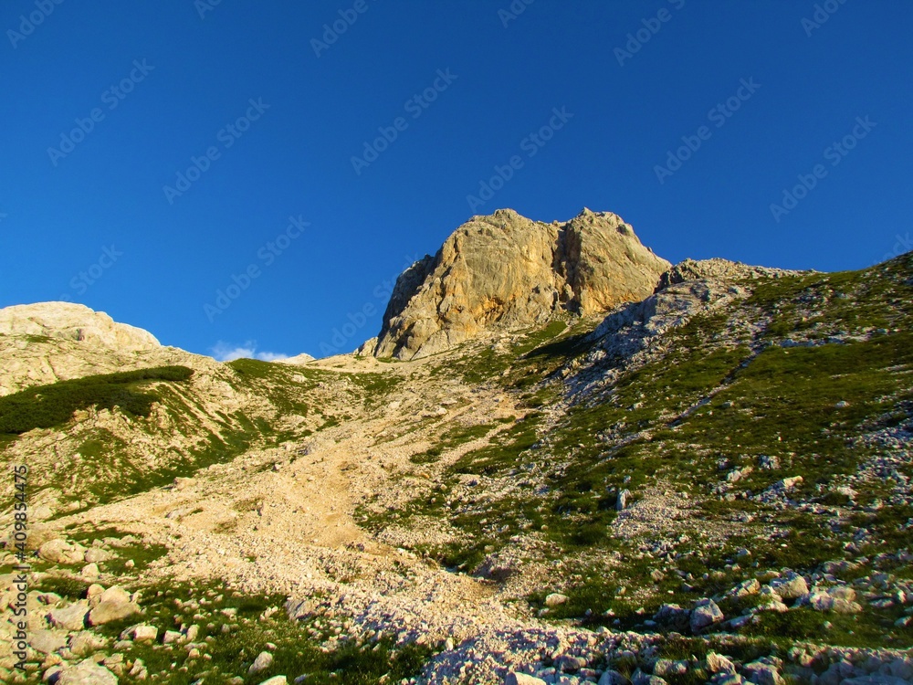 Rocky alpine landscape with grass and a mountain peak behind in Julian alps and Triglav national park, Slovenia