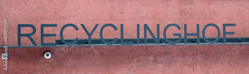 Schriftzug Recyclinghof in Metall vor rostroter Mauer - Hintergrund und Banner - Müllsammelstelle photo