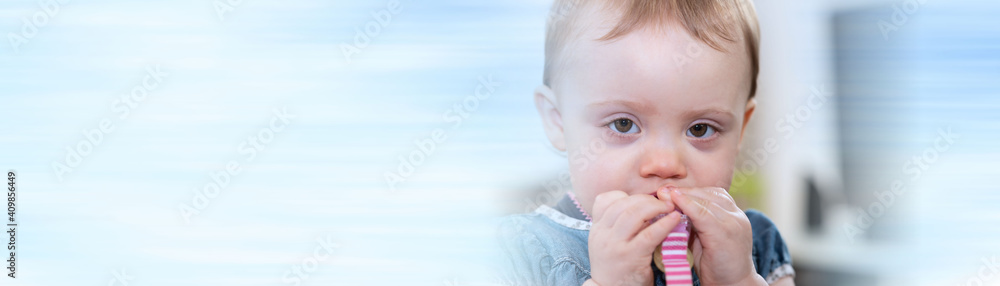Cute baby girl biting a plastic clip; panoramic banner Cute baby girl biting a plastic clip; panoramic banner