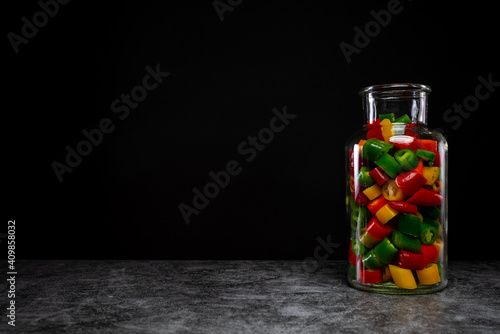 Colorful chili peppers in a glass on black background