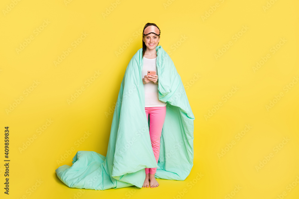 Full length photo of pretty woman dressed nightwear covering duvet holding modern device isolated yellow color background