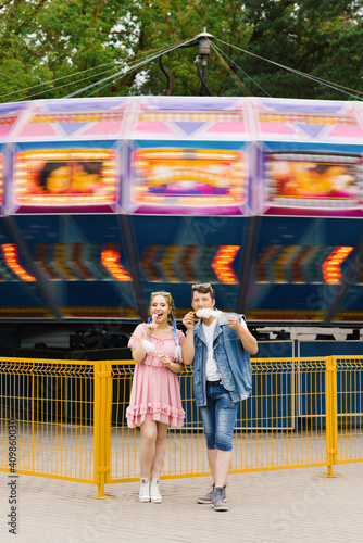 Happy couple in love enjoying each other in an amusement park. A guy and a girl eating cotton candy and laughing photo