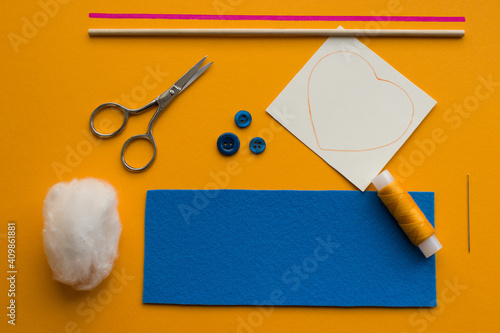 Step 1, making a valentine from blue felt with your own hands (DIY): preparing felt, a heart-shaped pattern, scissors, thread, cotton wool, a needle, buttons, ribbon, stick. photo