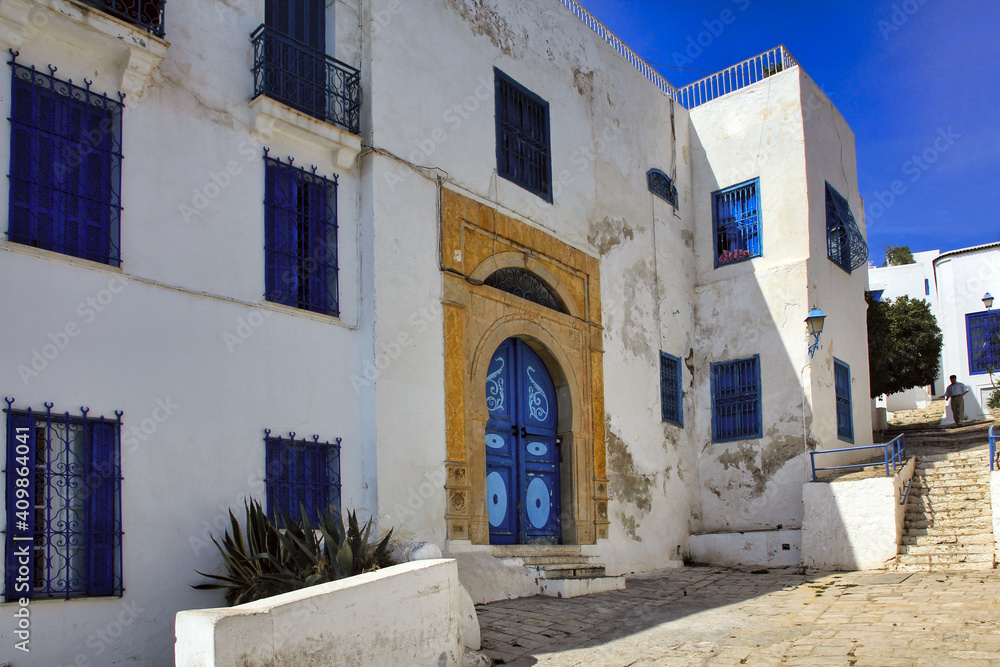 Weißes Haus mit blauen Fenstern und gelber Tür in Tunesien