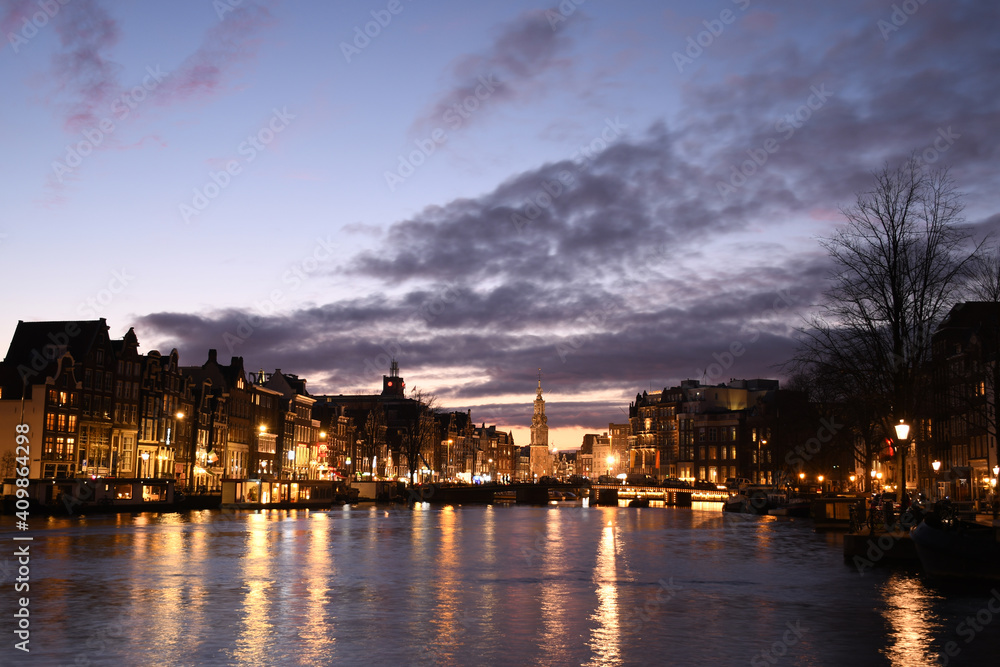 Evening view of the Munttoren (Mint Tower) and authentic Dutch architecture in Amsterdam on the Amstel river 