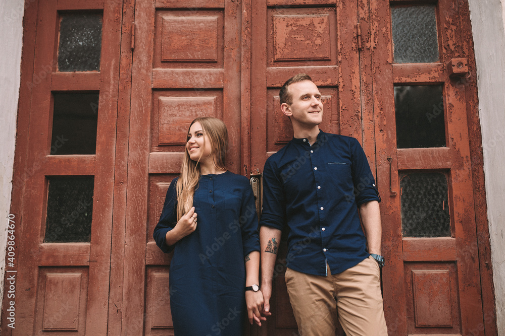 Happy beautiful young couple on the background of red old doors. Happy family concept Happy beautiful young couple on the background of red old doors. Happy family concept