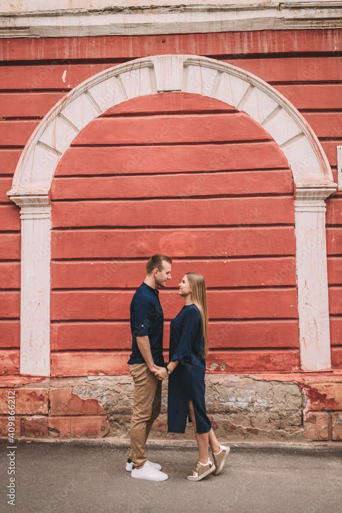 Young couple in love on the background of a red wall. Happy married couple on a walk in the city