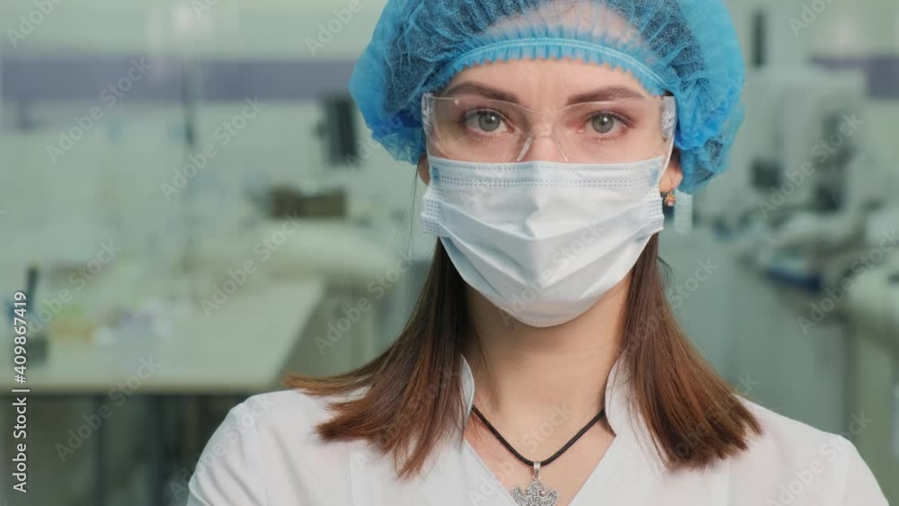 A nurse in a medical mask looks at the camera. Filming in a medical laboratory. A nurse in a medical mask looks at the camera. Filming in a medical laboratory.