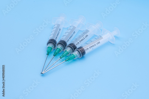 Clear plastic syringes with needles isolated against a bue background photo