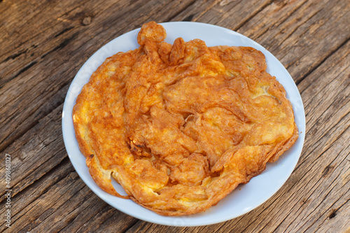 Crispy golden yellow omelette with plates on an old wooden floor is another simple dish in Thailand.