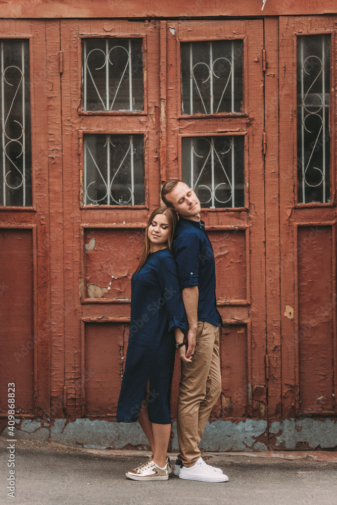 Happy beautiful young couple on the background of red old doors. Happy family concept