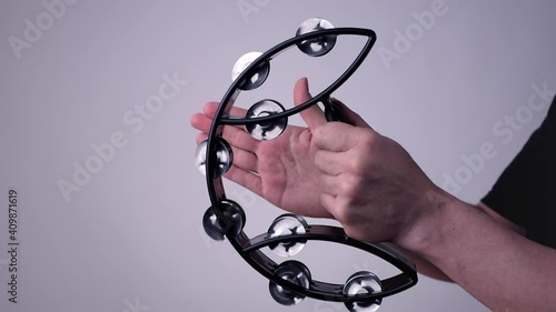 Caucasian hands holding and playing a black half moon shaped tambourine photo
