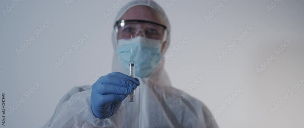woman in protection gear holding a syringe woman in protection gear holding a syringe