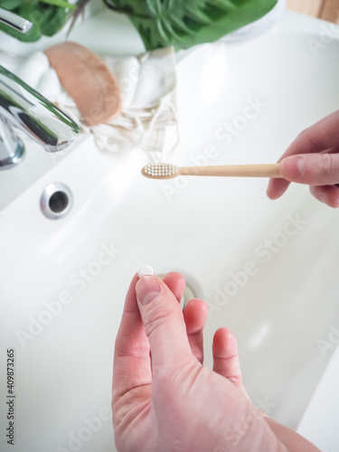 Hand holding a eco-friendly dental tab as toothpaste and bamboo toothbrush.