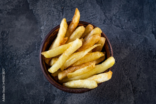 Bowl filled with crispy french fries on table