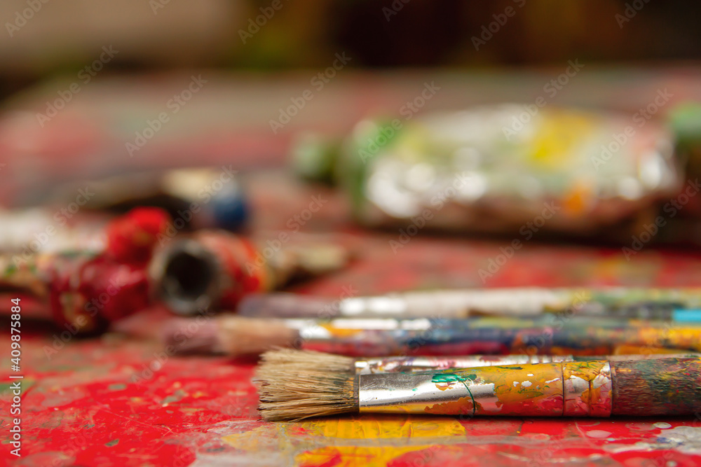 Artist colorful paint brushes on paint stained desk Artist colorful paint brushes on paint stained desk