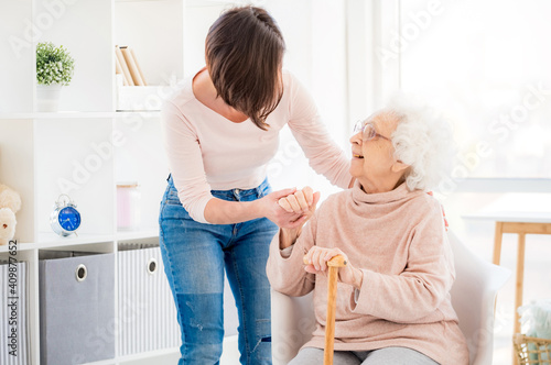 Foto Kind woman helping lovely old lady to stand from chair