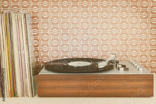 Vintage record player with record albums in front of seventies wallpaper