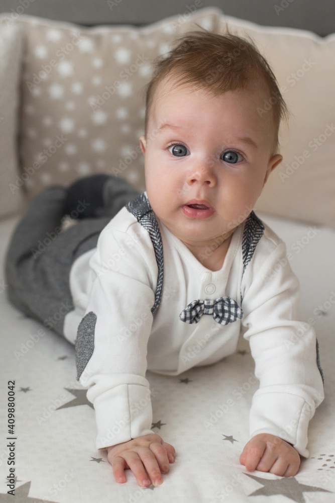 A cute little baby boy is surprised lying on the bed. Closeup portrait of newborn baby looking at camera A cute little baby boy is surprised lying on the bed. Closeup portrait of newborn baby looking at camera