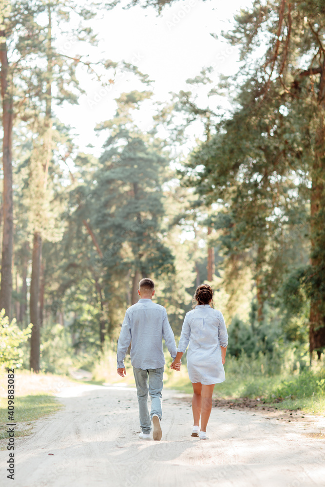young couple in love walking and enjoying the beautiful summer nature. woman and man, wearing in denim outfit are having date outdoors in the park. Romantic relationship. valentines day.