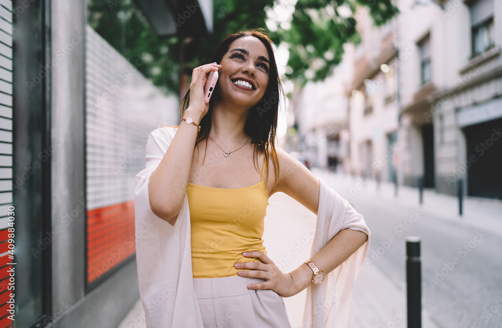 Joyful Caucaisan tourist laughing during friendly cellphone conversation in roaming, cheerful hipster girl rejoicing while making positive international call communication via smartphone application