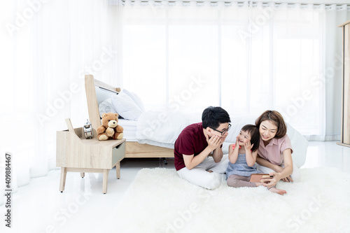 Girls with Down Syndrome cerebral learning disability, laughing, playing, parents in white bedrooms, teaching their children to watch educational materials using a smartphone. Happy education concept