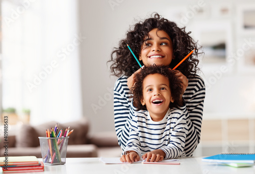 Tapet Ethnic mother and son laughing and grimacing and doing homework