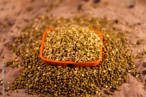 Plastic bowl and wooden spoon with Raw mung beans and moong dal rotation Mung bean  green moong dal with wooden spoon 