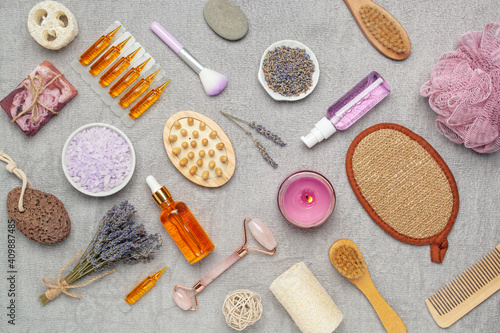 Lavender cosmetics background. Sea bath salt, oil, quartz face roller, wooden brush and flowers. Aromatherapy, spa. Top view . Flat lay. Copy space.