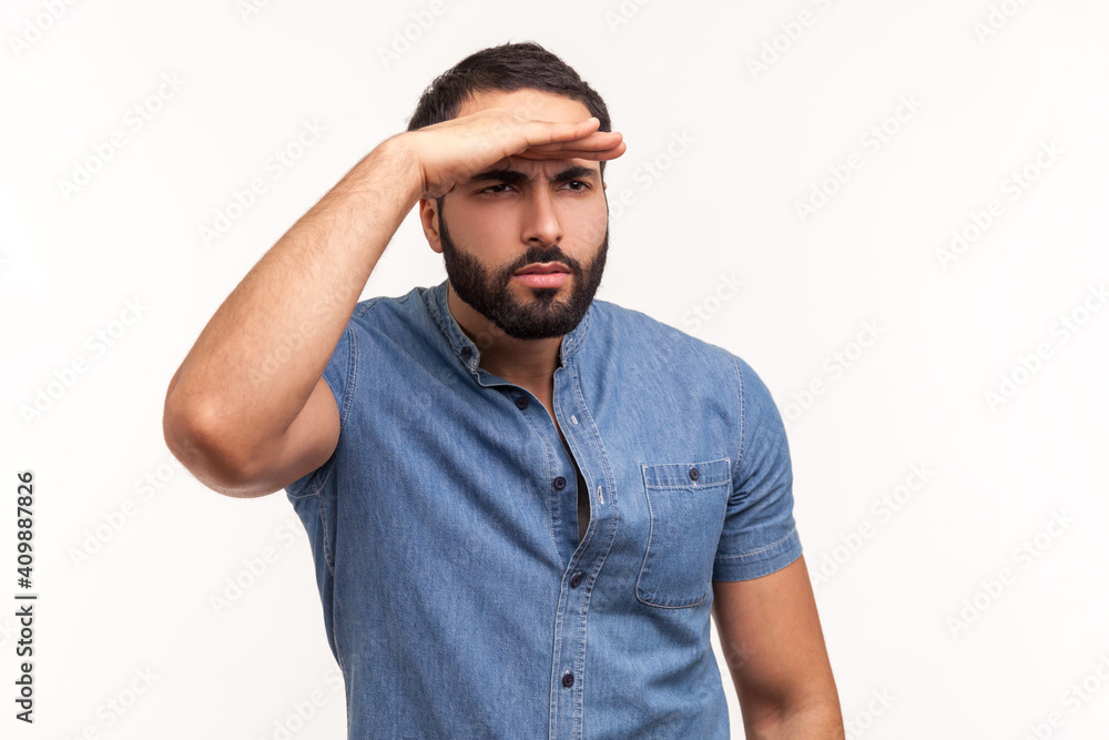 Thoughtful bearded man looking far away at distance with hand over head, attentively searching for bright future. Indoor studio shot isolated on white background Thoughtful bearded man looking far away at distance with hand over head, attentively searching for bright future. Indoor studio shot isolated on white background