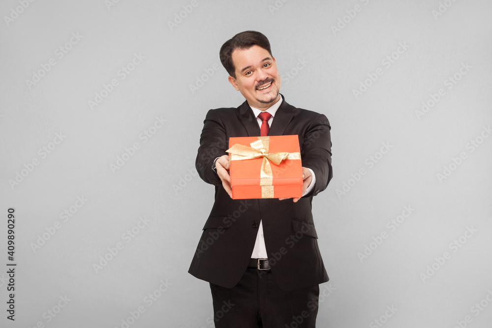 Business man holding red gift box. Present for you. Indoor, studio shot, isolated on gray background Business man holding red gift box. Present for you. Indoor, studio shot, isolated on gray background
