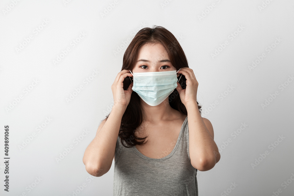 A beautiful young Asian girl is wearing a face mask to protect the pollution or covid19 virus disease. Grey background in the studio. Healthcare Pollution and virus pandemic concept. Copy and space A beautiful young Asian girl is wearing a face mask to protect the pollution or covid19 virus disease. Grey background in the studio. Healthcare Pollution and virus pandemic concept. Copy and space