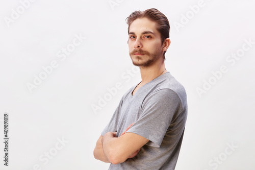 People concept - bearded face man cross arms. Friendly young man in gray shirt look in to the camera over grey background. Copy space © oleg_ermak