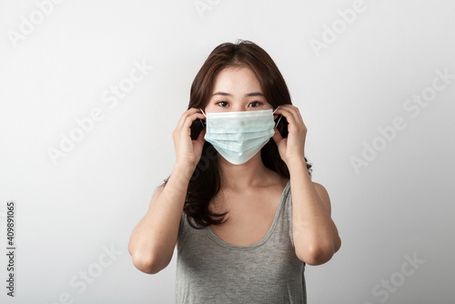 A beautiful young Asian girl is wearing a face mask to protect the pollution or covid19 virus disease. Grey background in the studio. Healthcare Pollution and virus pandemic concept. Copy and space
