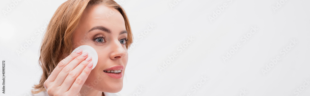 happy woman applying toner with cotton pad on face, banner