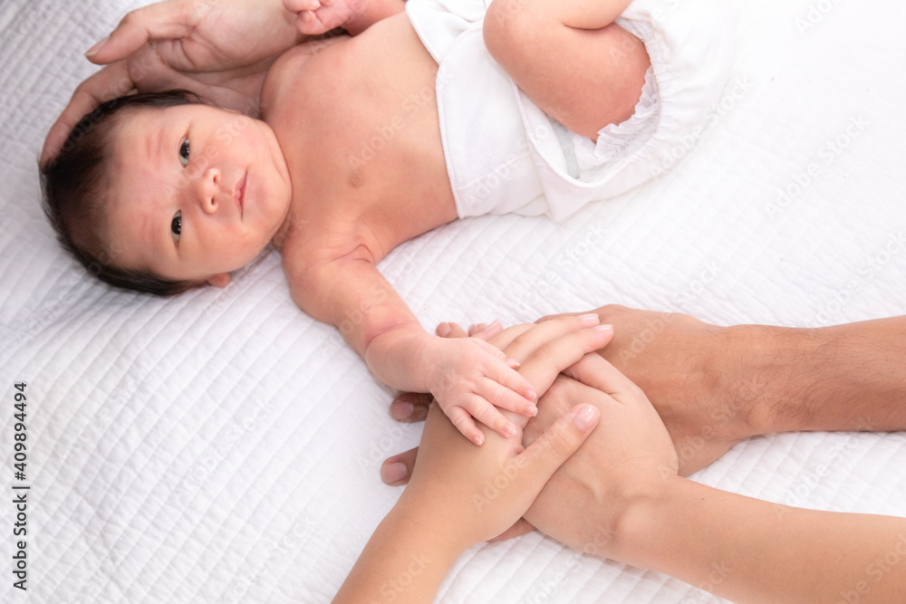 Beautiful shape hand of father, mother, daughter or sister hold tiny newborn hand on white bed with love, care and protection, infant look to mother face. baby hold his sister finger Beautiful shape hand of father, mother, daughter or sister hold tiny newborn hand on white bed with love, care and protection, infant look to mother face. baby hold his sister finger