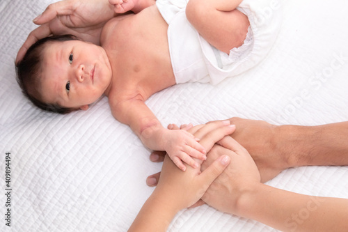 Beautiful shape hand of father, mother, daughter or sister hold tiny newborn hand on white bed with love, care and protection, infant look to mother face. baby hold his sister finger