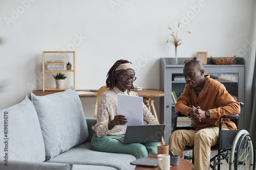 Portrait of African-American couple with handicapped man working from home together in modern interior, copy space photo