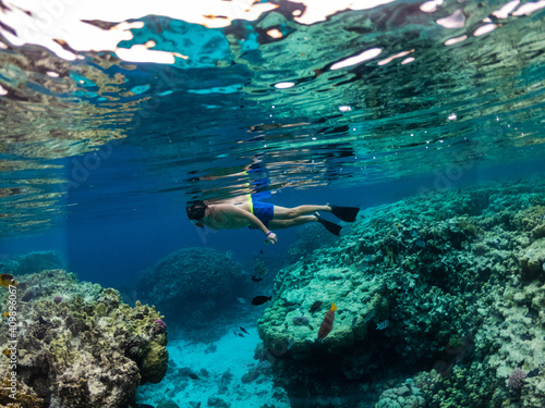 Young man snorkeling at coral reef in tropical sea