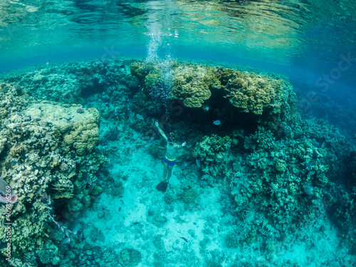 Fototapeta Naklejka Na Ścianę i Meble -  Young man dive at colorful coral reef in Red sea