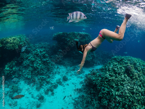 Young woman snorkeling at coral reef in tropical sea