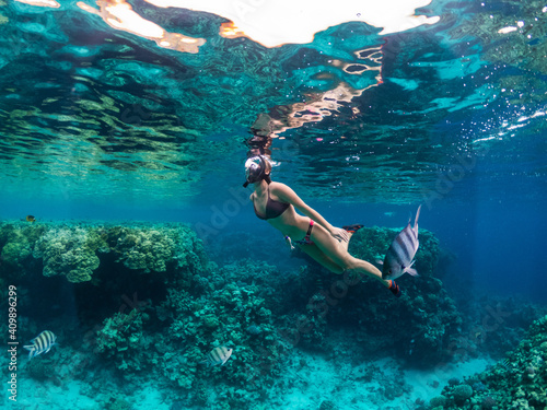 Young woman snorkeling at coral reef in tropical sea