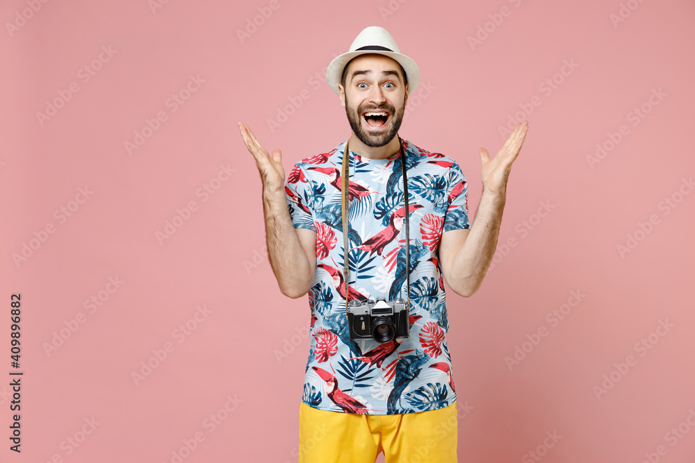 Surprised young traveler tourist man in summer clothes hat with photo camera spreading hands isolated on pink background. Passenger traveling abroad on weekends getaway. Air flight journey concept. Surprised young traveler tourist man in summer clothes hat with photo camera spreading hands isolated on pink background. Passenger traveling abroad on weekends getaway. Air flight journey concept.