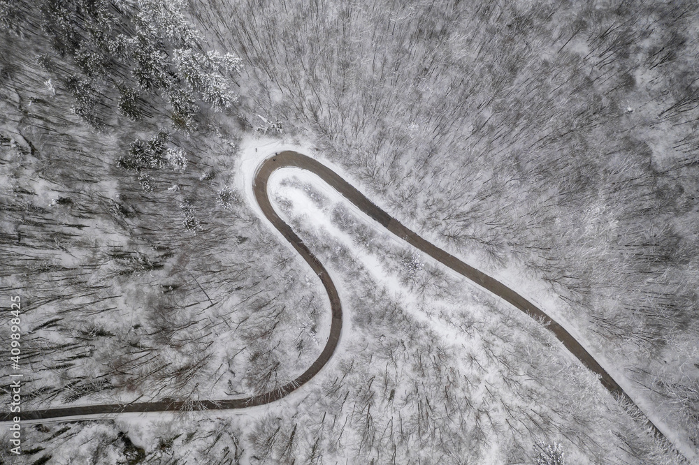 Top view with curvy mountain road in snow covered forest