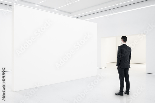 Businessman looking on blank presentation wall.